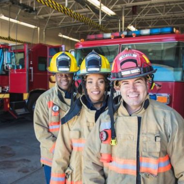 Three firefighters smile into the camera.
