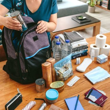 A woman packs a backpack with toiletries and emergency items.