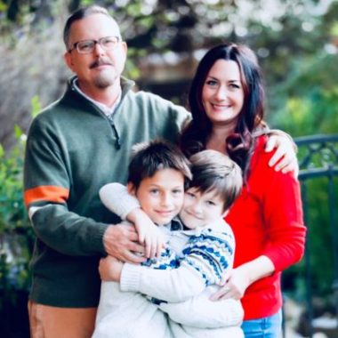 A father, mother and two young sons pose for a photo.