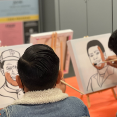 Two teens paint images of men.