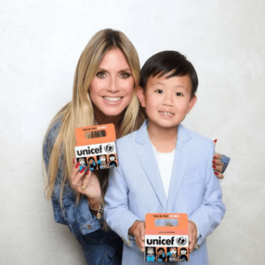 Model Heidi Klum and a young Asian boy hold Trick-or-Treat for UNICEF orange boxes for the organization's Halloween fundraiser.