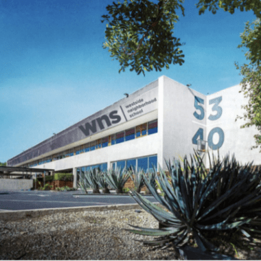 Photo of outside of Westside Neighborhood School, a white building surrounded by trees.